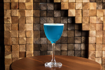 A blue sour alcoholic cocktail in a nick and nora glass - obrazy, fototapety, plakaty