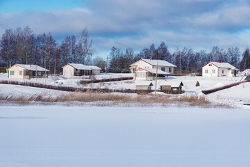 Fototapeta na wymiar Cottages by the frozen river at winter morning.