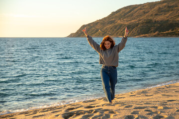 young woman raising her arms of happiness on the beach