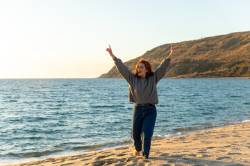 young woman raising her arms of happiness on the beach