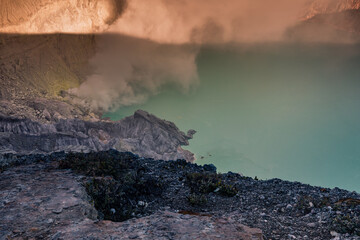 Sunrise over Kawah Ijen Volcano revealing acid turquoise lake and toxic sulfur gases next to illegal mining operation, Java, Indonesia