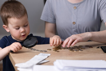 The little boy counts money. The child sorts through the coins on the table and counts the money. Business concept. Child and money. High quality photo