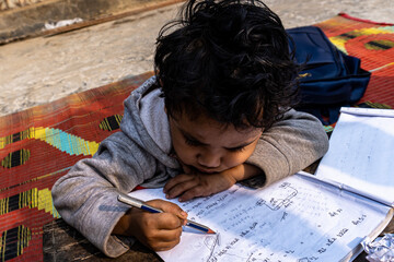 A baby boy wrighting something with a pencil and paper.