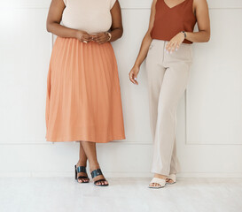 Fashion, formal and business woman friends at office against a wall in team conversation or chat. Discussion, planning and legs of professional corporate employee women in luxury outfits at workplace