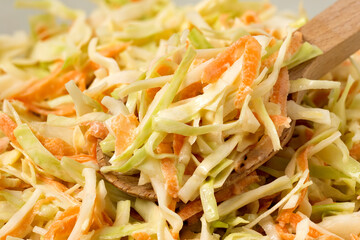 Detail of coleslaw with wooden spoon.