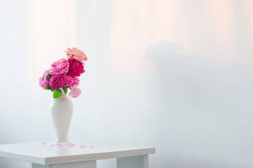 pink roses in white vase on table  on background white wall