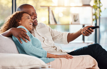 Couple, watching tv and laughing on sofa in home living room, bonding and hug. Interracial,...