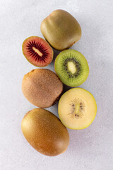 Different varieties of kiwi lie in a pile on the table. Halves of red, yellow and green kiwi. 