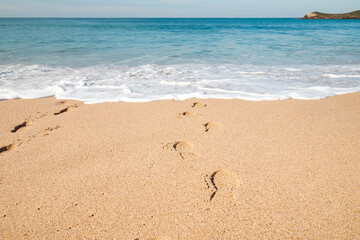 Footprints in the sand from a man sinking into the deep Atlantic Ocean on the sandy beach of Praia da Ilha do Pessegueiro near Porto Covo, western Portugal