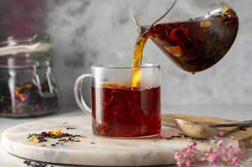Pouring freshly brewed black loose leaf tea in glass cup. Lifestyle drinking tea.