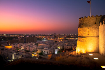 landscape showing top view of Bahrain, left side is Bahrain fort and rest is  houses with sunset