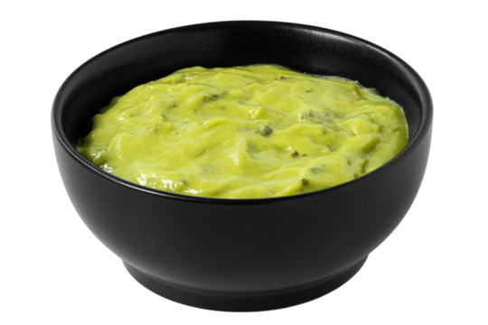 Guacamole dip in a black ceramic bowl isolated.
