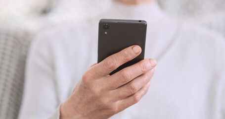 Elderly hands holding smartphone, front view, close-up, copy space. Concept of using new devices by old people, grandmothers, mothers.