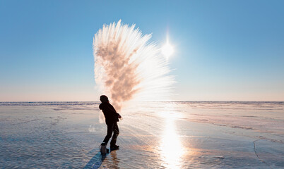 Man throwing boiling hot water freezing mid air.  Water condensate freezes and forms ice crystals - Baikal Lake, Siberia