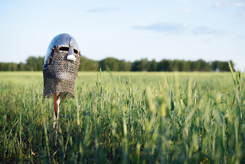 The ancient sword with knight helmet stuck in the ground background.