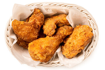 Crispy fried chicken pieces in a white woven basket isolated on white from above. - 587665063
