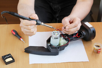 Hands soldering wire to electric motor when repairing tool