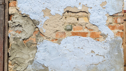 The old wall of the house. Blue crumbling wall of the building. The wall of an old barn. Orange brick in the wall of an old building