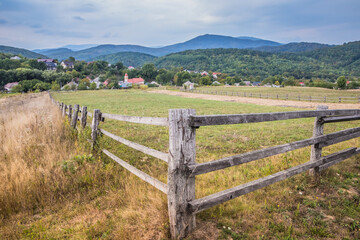 Fototapeta na wymiar Cloudy morning in a small village in the mountains. Territory fenced with a deevyannim fence for livestock entry. Country road in the mountains. Carpathians. Polyana. Ukraine