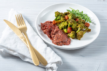 Breakfast in a white plate of broccoli vegetables, herbs and ham slices