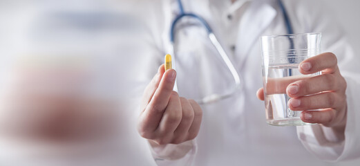 Doctor holding pill and a glass of water.