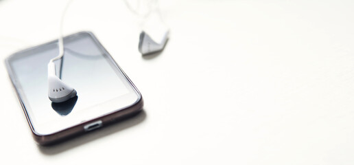 Smartphone with a earphones on white desk.
