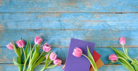 Fotobehang beautiful spring flowers, row of pink tulips flowers with books on wooden blue background, concept, flat lay, negative space,free copy space © Kirsten Hinte