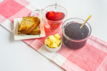 Breakfast with cranberries, butter, toast and red hot tea in a heart shaped cup, and yellow roses in a green vase