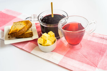 Breakfast with cranberries, butter, toast and red hot tea in a heart shaped cup, and yellow roses in a green vase