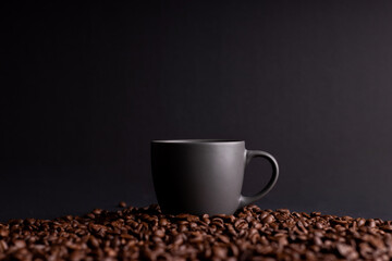 a coffee mug among coffee beans, black isolated background