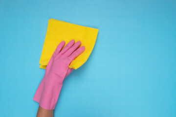 woman wearing pink cleaning gloves on light blue background, holding cleaning cloth