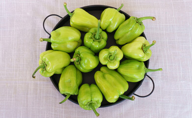 Uncooked green peppers in black tray top view.