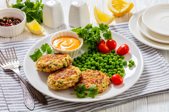 crab cakes with sauce, green peas, tomatoes