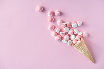 Colorful bright meringues in waffle cookies lie on a pink background