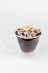 Iced coffee with lemon and ice cubes in glass on white background