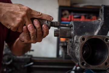 Mecánico reparando pieza automotor en su taller