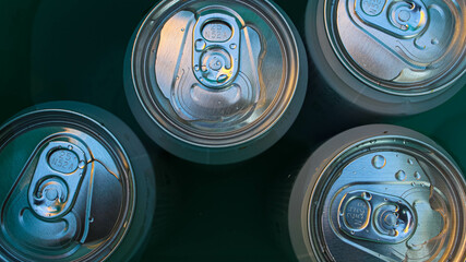 Beer in aluminum cans is cooled in a green bucket with cold water - obrazy, fototapety, plakaty