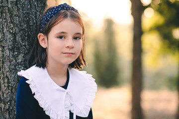 Cute child girl 6-7 year old wear school dress with white collar outdoor over nature background....