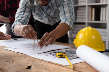 Close up of engineers consulting team close up to design building blueprints paper for clients with building models to work at office.