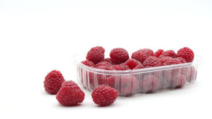close up of raspberries in a transparent plastic package on a white background