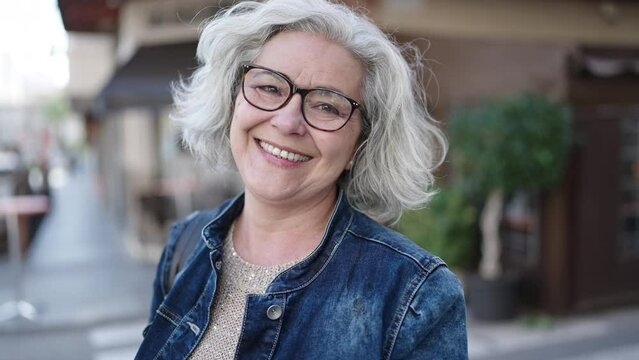 Middle age woman with grey hair smiling confident at street