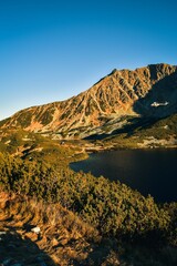 Naklejka premium Beautiful summer mountain landscape. Mountain slopes reflecting in the lake. Photo taken in the Valley of Five Ponds in the Polish Tatra Mountains.