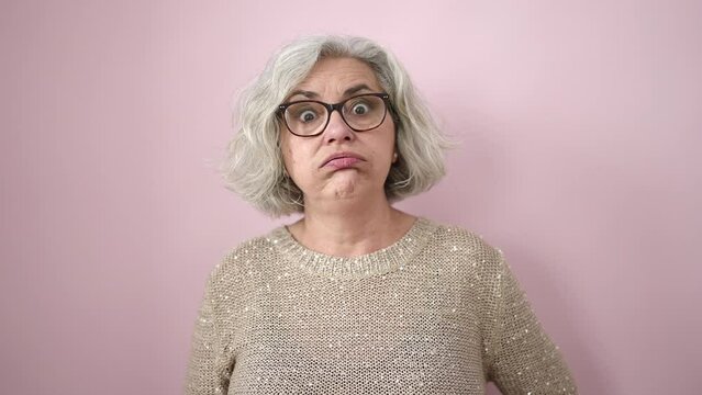 Middle age woman with grey hair worried with hand on forehead over isolated pink background