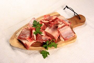 Raw beef ribs on wooden kitchen board, white background