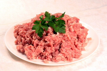 Ground pork on a plate decorated with green parsley leaves