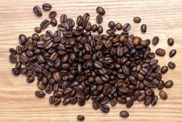 Obraz na płótnie Canvas Random pile of roasted coffee beans on a wooden board background.