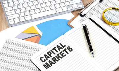 Fototapeta premium CAPITAL MARKETS text on a paper on chart background