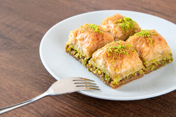 Turkish baklava with pistachio in plate.A plate baklava on wooden background,top view
