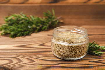 Fresh rosemary and dry spice in a plate and spoons on a brown textured background. Fresh spice herbs. Seasoning for meat and fish. Recipe.Organic bouquet of fresh rosemary on the table.Place for text.
