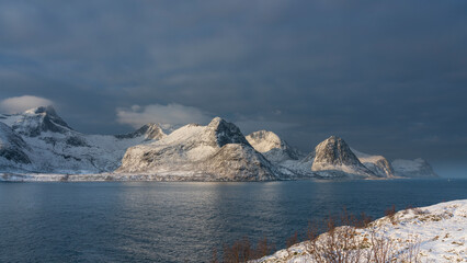 &Oslash;yfjorden im Morgenlicht, mit den schneebedeckten Bergen von Senja, genannt Segla, Kongan und Skultran im Hintergrund. Norwegen im Winter, mit Atlantik und Fjord 
